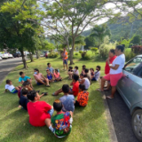 Children-of-the-Faanui-Ward-of-the-Bora-Bora-Stake-and-friends,-gather-and-get-instructions-before-cleaning-up-a-park.-French-Polynesia,-February-2022