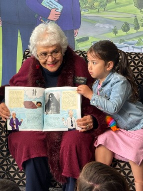 Aunty Rangi reads the Church history children's book to a young child.