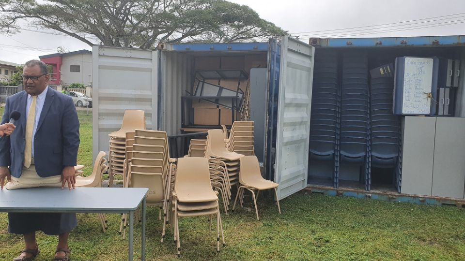 Elder-'Inoke-Kupu,-Area-Seventy-for-the-Church,-stands-next-to-opened-containers-of-surplus-furniture-from-New-Zealand-that-will-be-used-for-schools-in-Tonga.-September-2021
