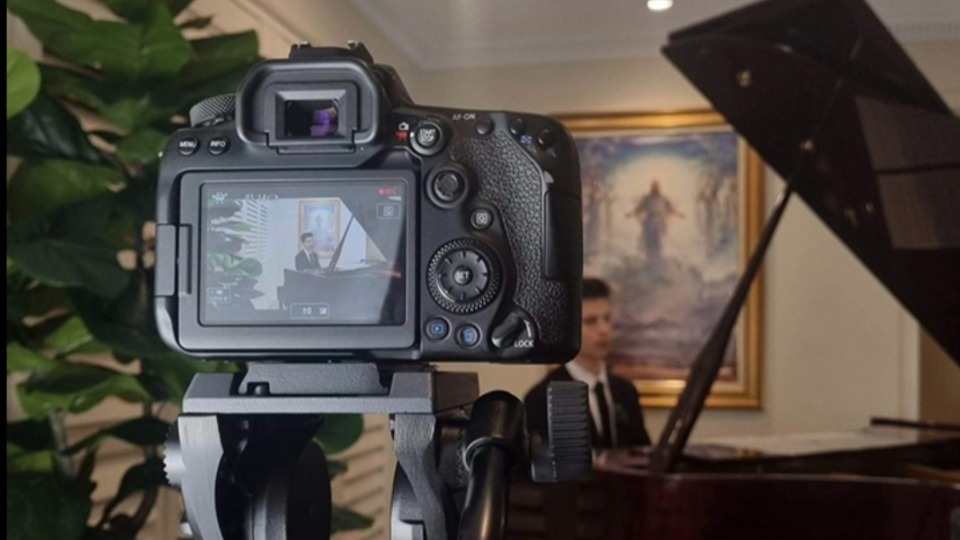 A missionary plays the piano for a music video aimed at inviting individuals to follow Jesus Christ.