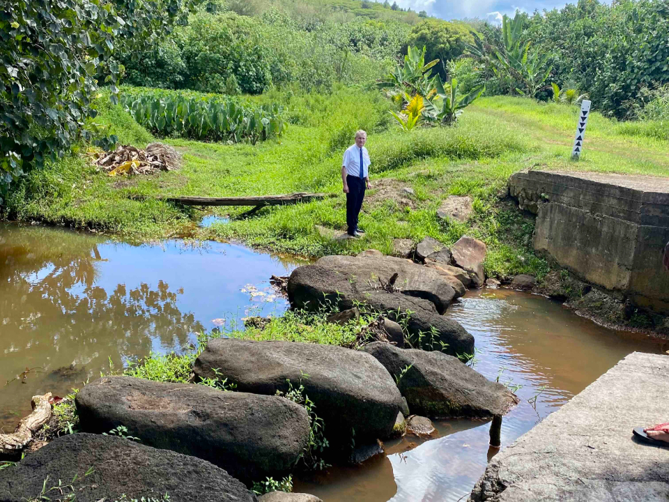 Elder-LeGrand-R.-Curtis-Jr-stands-on-the-trail-that-members-built-in-the-1890's-to-cross-the-river.-French-Polynesia,-March-2022